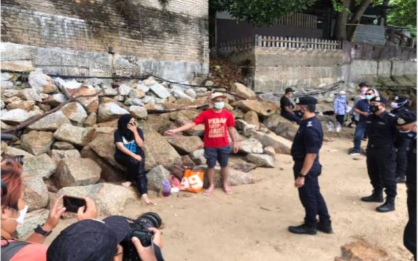 Mohd Shuhaily (tengah) sedang bertanya sesuatu kepada pengunjung di salah sebuah pantai di Tanjung Bungah.