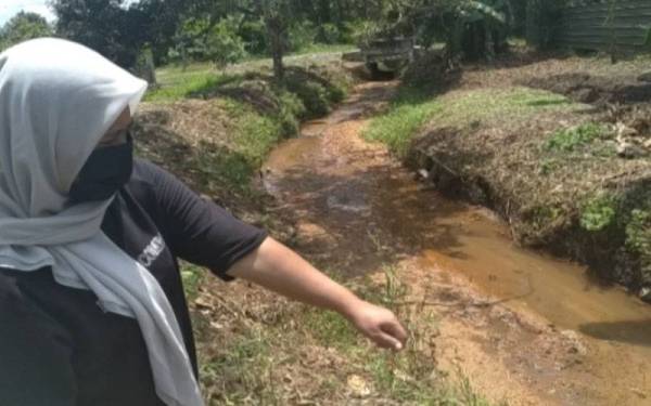 Rozina menunjukkan keadaan anak sungai berdekatan rumahnya di Kampung Baru Sri Aman, Seelong, Kempas, Johor Bahru ketika ditemui pemberita pada Khamis.