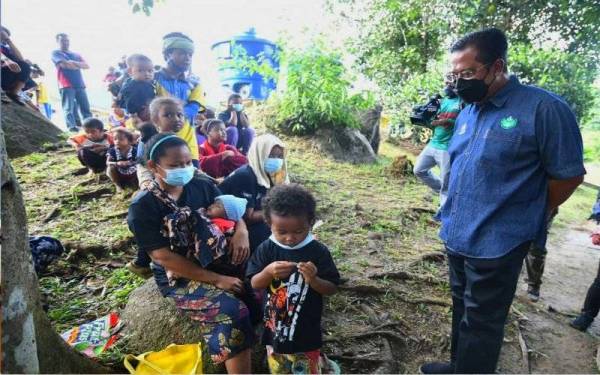 Abdul Rahman (kanan) beramah mesra dengan orang asli pada misi vaksinasi masyarakat orang asli di Pos Gob pada Sabtu.