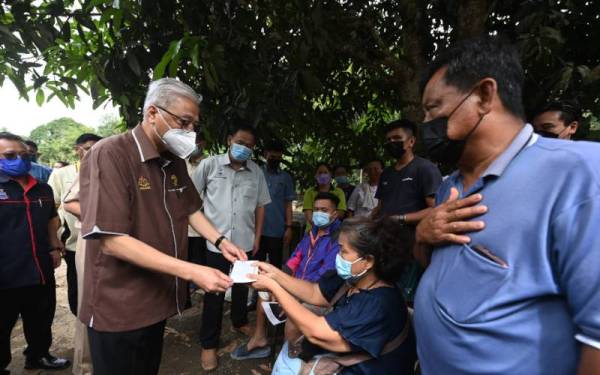 Ismail Sabri (dua dari kiri) menyampaikan sumbangan kepada penduduk yang mengalami kerosakan rumah teruk akibat dilanda tanah runtuh di Kampung Madsiang semasa lawatan kerja ke Sabah pada Isnin lalu. - Foto fail Bernama