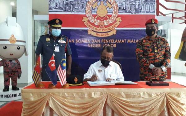 Dr Ismail menandatangani buku pelawat sambil disaksikan Yahaya (kanan) semasa melakukan lawatan kerja ke Ibu Pejabat JBPM Johor, di Kangkar Tebrau, Johor Bahru pada Ahad.