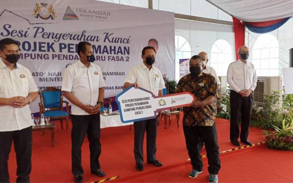 Hasni (tiga dari kiri) menyerahkan kunci rumah kepada penduduk bagi projek penempatan semula perumahan di Kampung Pendas Baru Fasa 2 di Iskandar Puteri pada Ahad.