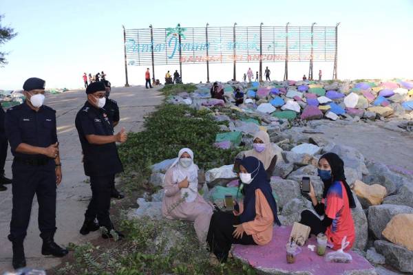 Shafien (dua dari kiri) menunjukkan isyarat bagus kepada pengunjung di Pantai Irama Bachok yang lengkap vaksinasi Covid-19 semasa melakukan pemantauan.