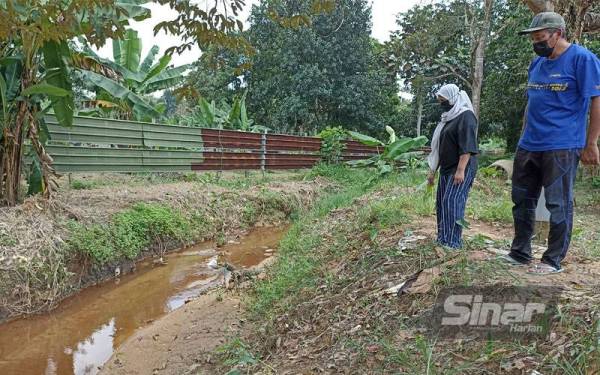 Rozina dan Abd Rahim melihat keadaan anak sungai berdekatan rumahnya selepas seminggu insiden pencemaran sisa kimia di Kampung Baru Seelong Kempas, Johor Bahru.