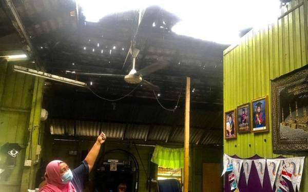 Pembantu kedai makan, Nurul Irdani Azmi, 36, menunjukkan bumbung rumahnya yang rosak dipukul ribut dalam kejadian pada Selasa.