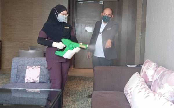 Hezrin (kanan) ketika memantau staff hotel menjalankan proses sanitasi di setiap bilik Hotel Renaissance, Permas Jaya di Pasir Gudang pada Khamis.