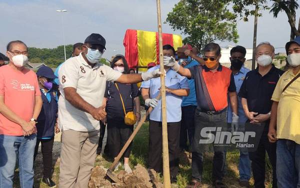 Gunaraj (dua dari kiri), Loy Sian dan Mohamad menanam pokok tekoma di sepanjang Jalan Sungai Jati, di sini pada Ahad.