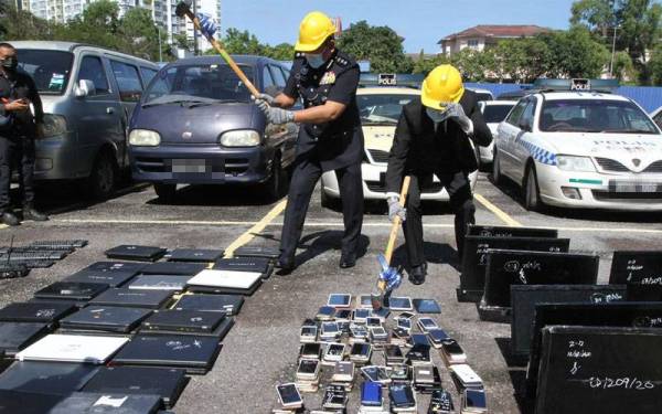 Muhammad Idzam (Kiri) melakukan gimik pelupusan barang kes di Pondok Polis Alam Damai di sini pada Selasa.