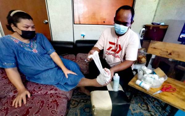 Mohd Zaki bersihkan luka bisul di kaki Suzila ketika menerima kunjungan Pertubuhan Kebajikan Asnaf Setia Kasih Negeri Sembilan di rumah sewanya di Taman Seremban Jaya, Seremban pada Rabu.