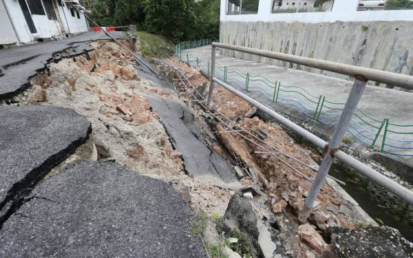 Tembok penahan dan jalan yang runtuh dalam kejadian di Lengkok Halia, Georgetown pada Jumaat.