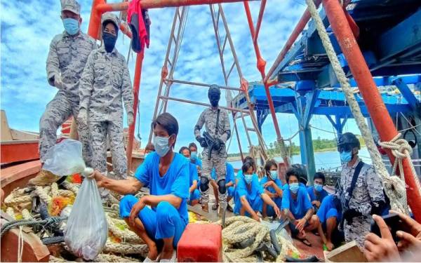 Khairun Dalilah (dua dari kiri) memeriksa hasil laut yang dicuri nelayan asing Vietnam dalam sidang media di Pasir Puteh, pada Jumaat.