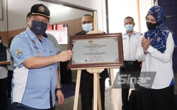 Alexander (kiri) menandatangani plak simbolik perasmian Pusat Pengumpulan dan Pengagihan Food Bank Malaysia (Zon Utara) di RTC Gopeng.