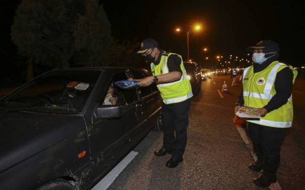 Azrin memberikan risalah keselamatan kepada salah seorang pemandu kenderaan pada Operasi Bersepadu JPJ di Jalan Persiaran Senawang, Seremban pada malam Sabtu.