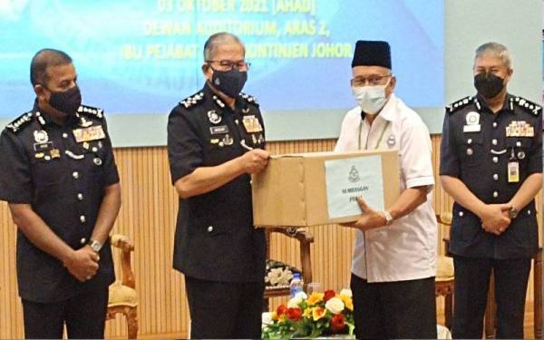 Mazlan (dua dari kiri) menyerahkan sumbangan kepada pesara polis di IPK Johor pada Ahad.