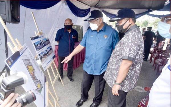 Hamzah (tengah) melihat pelan pembinaan bangunan baharu IPK Terengganu pada majlis pecah tanah pada Isnin.