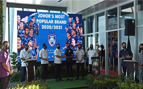 Hasni (empat dari kiri) menyampaikan Anugerah Pelancongan Johor 20/21 Kelab Bola Sepak Johor kepada Mohd Farizal Marlias pada Majlis Pelancaran Johor Tourism Interchange (JTI) di Menara JLand, Johor Bahru pada Isnin.