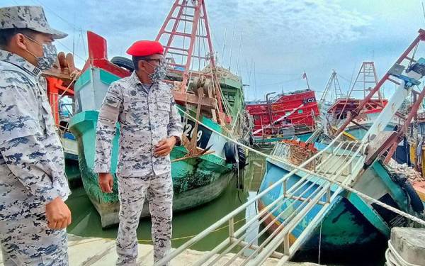 Mohd Zubil (kanan) bersama Syed Nor Adli meninjau kapal nelayan asing yang berjaya dirampas di Pusat Tahanan Vesel Maritim Malaysia Kelantan Tok Bali, Pasir Puteh pada Isnin.