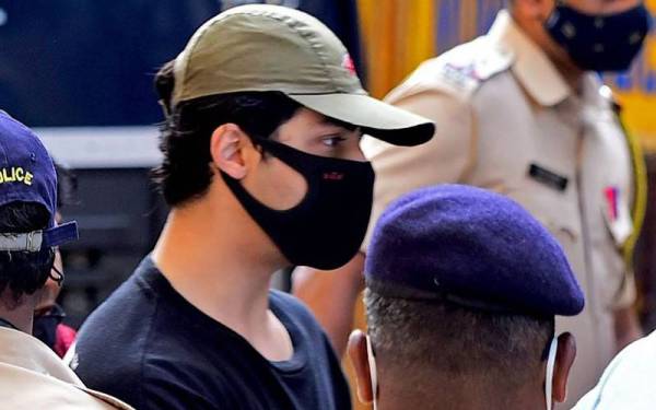 Aryan Khan dikawal oleh pegawai penguat kuasa di luar pejabat Biro Kawalan Narkotik, di Mumbai pada 3 Oktober lalu. - Foto AFP