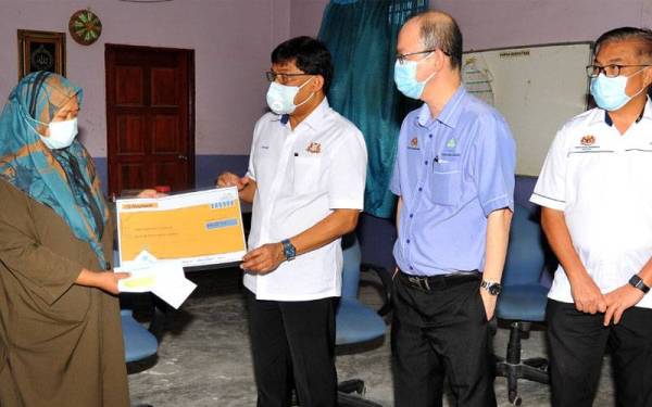 Mohd Izhar (dua dari kiri) menyampaikan bantuan Perkeso kepada Nor Fairus yang kematian suaminya akibat Covid-19 sambil diperhatikan Tong Sing Chuang (dua dari kanan) di Flat Serantau, Larkin, Johor Bahru.