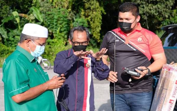 Arifin (kiri) mendengar taklimat Pengerusi Kelab Radio Amatur Komunikasi Bencana-Squad 99 Terengganu, Amrun (tengah).