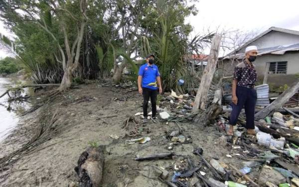 Abdul Yunus (kiri) meninjau kawasan belakang kediaman Abu Bakar yang hampir dengan tebing Sungai Kurau yang kini diancam hakisan.