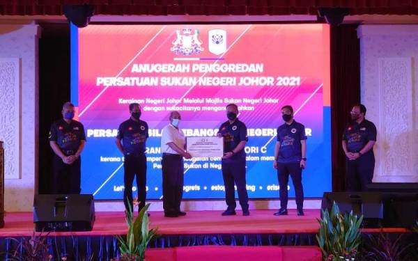 Hasni Mohammad (tiga dari kanan) menyerahkan sijil Anugerah Penggredan Persatuan Sukan Negeri Johor sempena pelancaran Hari Sukan Negara 2021 Peringkat Negeri Johor di Iskandar Puteri pada Sabtu.