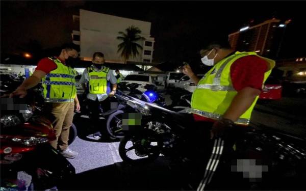 Mohd Kamarul (tengah) melihat motosikal yang disita selepas berakhirnya Op Samseng Jalanan pada malam Ahad.