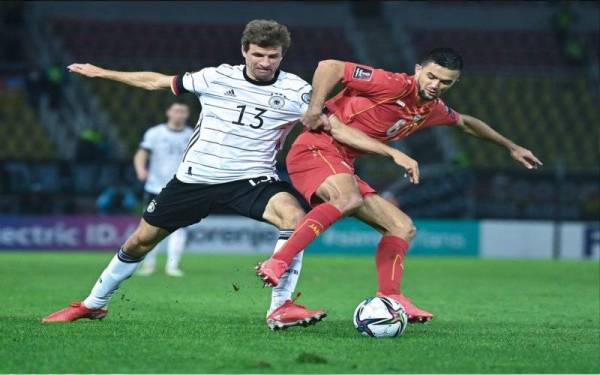 Thomas Mueller (kiri) cuba melepasi halangan pemain Macedonia Utara dalam aksi di Skopje.