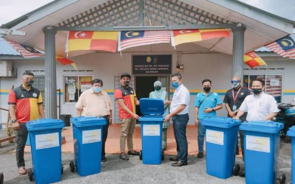 Mohd Idris (empat dari kanan) menyerahkan tong sampah kepada Daing (kiri) pada majlis penyerahan di Kampung Melayu Ampang, Ampang pada Selasa.