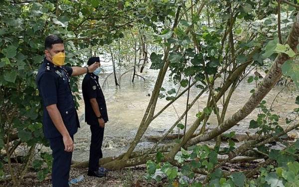 Anggota polis menunjukkan lokasi mayat keempat PATI yang terdampar di Pantai Rambah, Pontian pada Selasa.