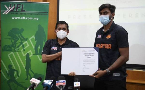 Radhakrishnan (kiri) menunjukkan memorandum perjanjian persetujuan untuk penghantaran jurulatih Roobenraj ke Qatar di Wisma UFL pada Selasa. - Foto Bernama