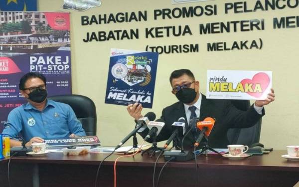 Muhammad Jailani (kanan) menunjukkan plakad Rindu Melaka sebagai tarikan pelancong domestik ke negeri itu susulan kebenaran rentas negeri.