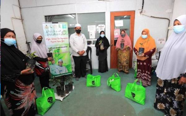 Wan Roslan (tiga dari kiri) melakukan simbolik penyerahan kit tanaman kepada penerima di Pusat Khidmat DUN Pengkalan Kubor, Tumpat pada Rabu.