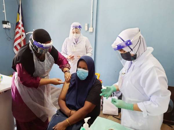 Dr Nor Azimi (kiri) sedang menyuntik vaksin kepada salah seorang golongan gelandangan di kawasan Jang Wong Ah Jang pada program yang diadakan pada Rabu.