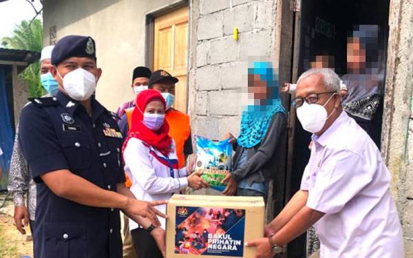 Mohd Farid (kanan), Mohamad Ismail (kiri) dan Rohayu (dua dari kiri) menyampaikan bakul makanan kepada keluarga peserta Hijrah Keluarga di Kampung Pauh Sembilan, Perupok, Bachok pada Khamis.