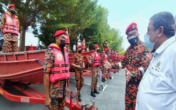 Zainal (dua dari kanan) memberikan penerangan kepada Nik Mohamed Noor semasa turun melihat program simulasi persiapan banjir bagi menghadapi monsun Timur Laut di pekarangan Ibu Pejabat JBPM Kelantan di Tunjong, Kota Bharu pada Khamis.