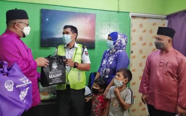 Ahmad Marzuk (kiri) menyampaikan bantuan makanan ketika lawatan MAIWP Jejak Asnaf di rumah keluarga Terunah (dua dari kiri) di Kuala Lumpur pada Rabu.