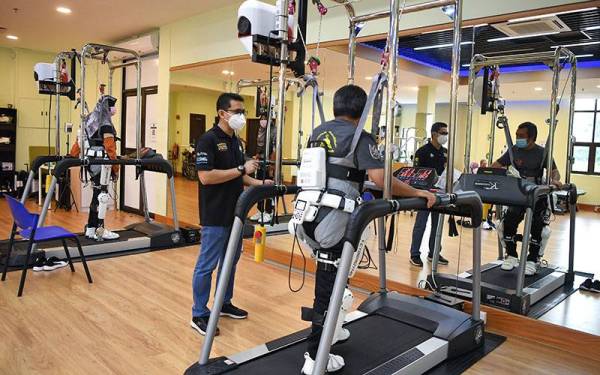 Mohd Zoolfaiz (dua, kiri) memantau fisioterapi pesakit yang menggunakan Robot Suit Hybrid Assistive Limb. - Foto Bernama