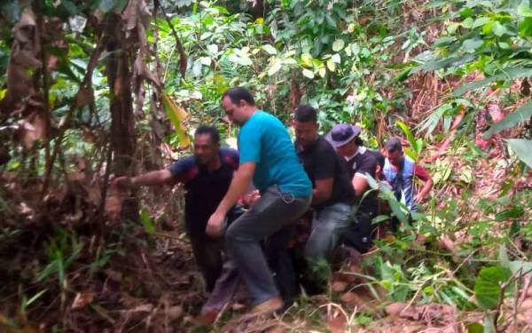 Anggota penyelamat membawa keluar wanita yang ditemui selamat di tepi jalan Kuala Balah, Jeli pada Jumaat.