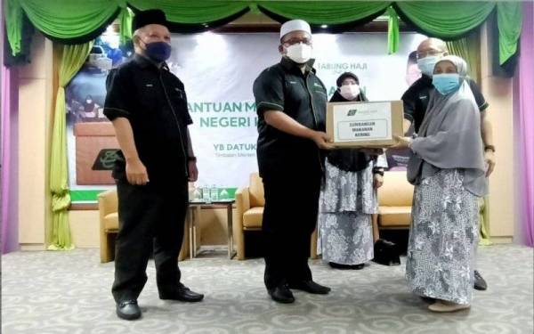 Ahmad Marzuk (dua dari kiri) menyampaikan bantuan pek makanan kepada keluarga asnaf yang terkesan akibat pandemik Covid-19 di Bangunan Tabung Haji (TH) Kelantan, Kota Bharu pada Sabtu.