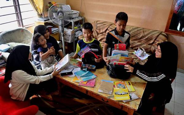 Mazkiah Mohd Salleh,40, (tiga dari kiri) melihat persiapan anak-anaknya menjelang pembukaan sesi persekolahan pada Ahad. -Foto: Asril Aswandi Abd Shukor