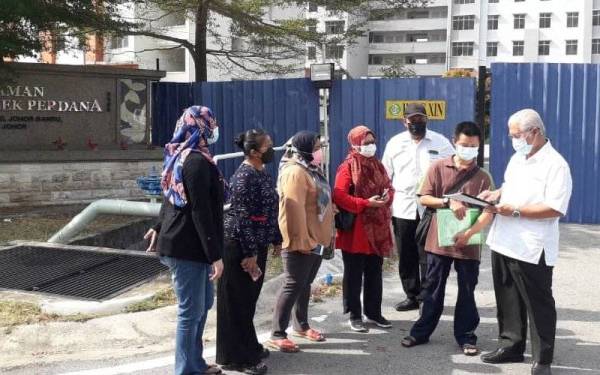 Hassan (kanan) melihat dokumen dan surat jual beli daripada pembeli semasa melawat projek perumahan terbengkalai di Taman Seri Molek Perdana, Plentong, Pasir Gudang, pada Ahad.