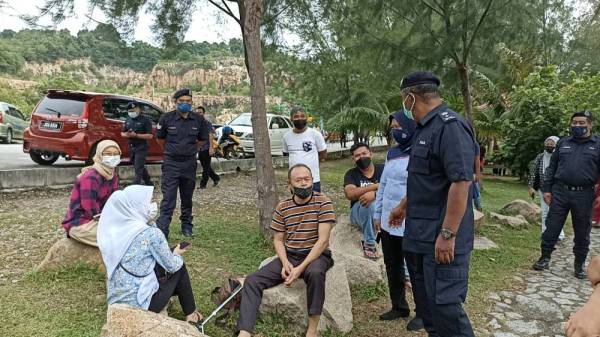 Anggota polis melakukan pemantauan SOP ke atas pengunjung di Pantai Minyak Beku Batu Pahat pada Ahad. 