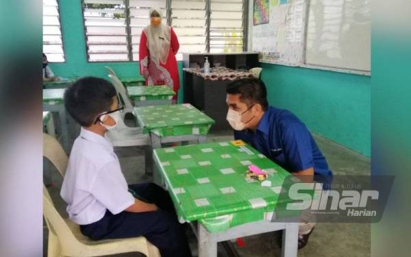 Senator Datuk Dr Mohd Radzi Md Jidin bermesra dengan murid Tahun 1 Sekolah Kebangsaan Tunku Besar Tampin, Ammar Fahmi Hishamuddin, sempena tinjauan hari pertama persekolahan bagi negeri Fasa 4 Pelan Pemulihan Negara (PPN) pada Isnin.