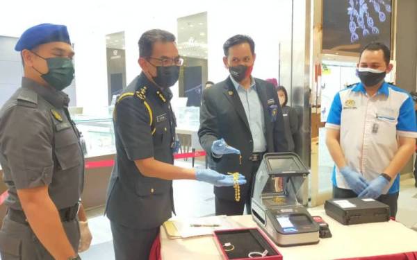 Azman (dua dari kiri) menunjukkan demo pemeriksaan dan pengujian ketulenan emas di salah sebuah kedai emas di KTCC Mall, Kuala Terengganu, pada Isnin sambil diperhatikan Pengarah KPDNHEP Terengganu, Saharuddin Mohd Kia (dua dari kanan).