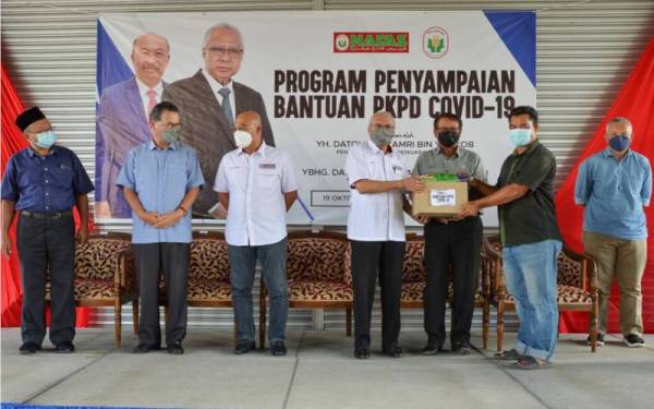 Zamri (empat kiri), menyerahkan sumbangan kepada wakil unit sempena Majlis Penyampaian Sumbangan PKPD COVID-19 di Pertubuhan Peladang Kawasan (PPK) Gerai, Besut.