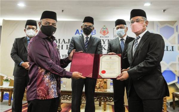 Mohd Daud (tengah) menyaksikan penyerahan surat watikah yang disampaikan oleh Mohd Nizam (dua, kiri) kepada Amiruddin (kanan) pada Majlis Penyerahan Watikah Pelantikan Mutawalli di Bangunan PERKIM, MAIWP, pada Khamis. Turut sama, Idris (dua, kanan) dan Setiausaha MAIWP Datuk Mohd Ajib Ismail (kiri). - Foto Bernama