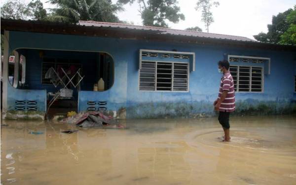 Penduduk setempat Roszaidi Zakaria, 50, meredah air yang masih bertakung di kawasan rumahnya selepas kejadian banjir malam tadi ketika ditemui di Kampung Temerlok, Terong pada Khamis. - Foto Bernama 