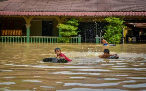 Kanak-kanak bermain air di halaman rumah hari ini selepas beberapa rumah di Kampung Sri Tanjung, dilimpahi banjir berikutan hujan lebat semalam. - Foto Bernama