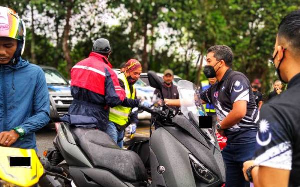 Azril (dua dari kiri) mengagihkan risalah berkaitan dadah kepada peserta konvoi ke Rompin untuk diedarkan kepada orang ramai di lokasi-lokasi terpilih.